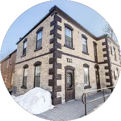 Exterior view of a IIPC Canada building at 132 in a historic stone architecture style, cropped in a circular frame.